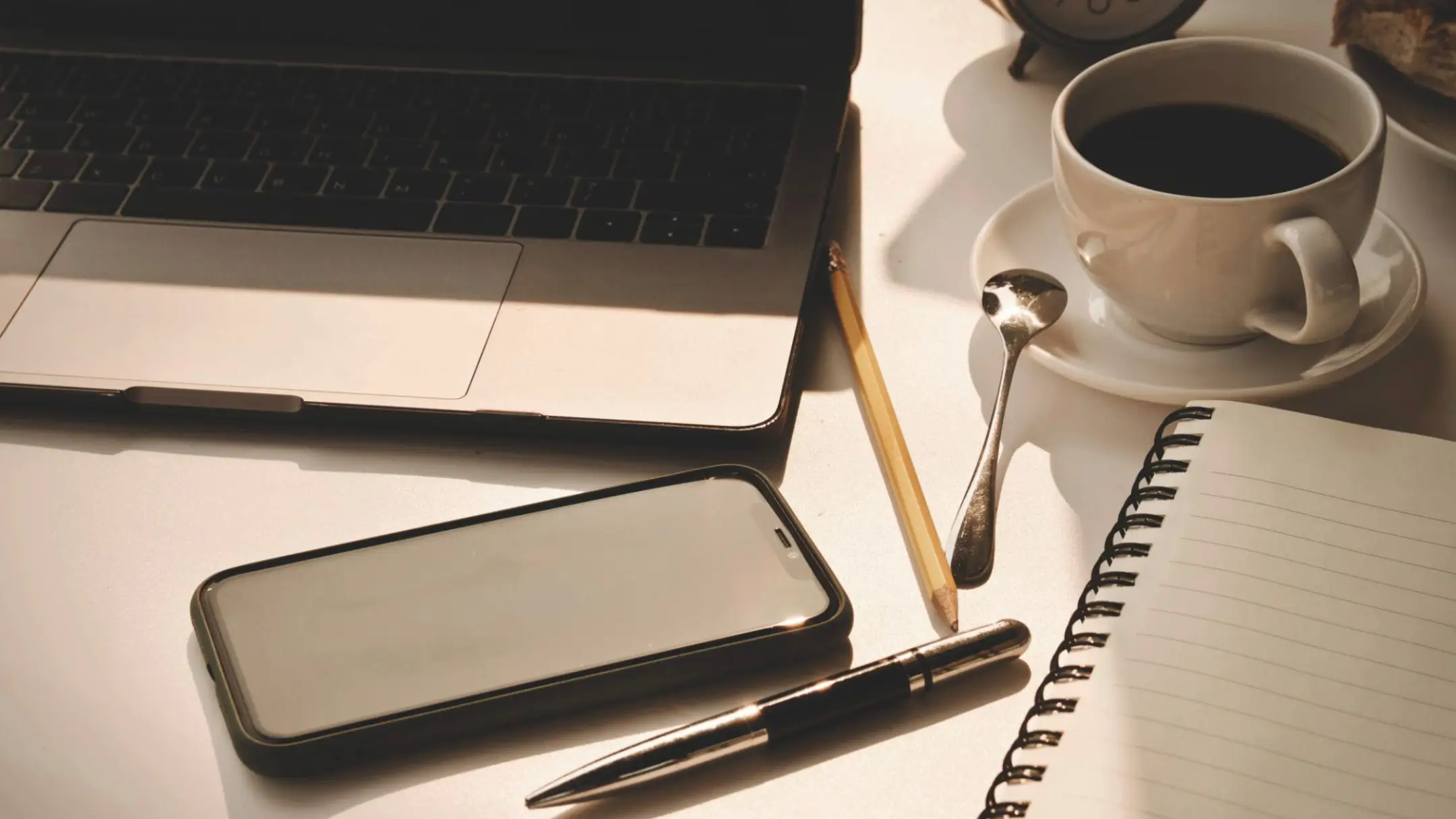 Laptop, smartphone and notebook on a desk representing everyday routines and screen time
