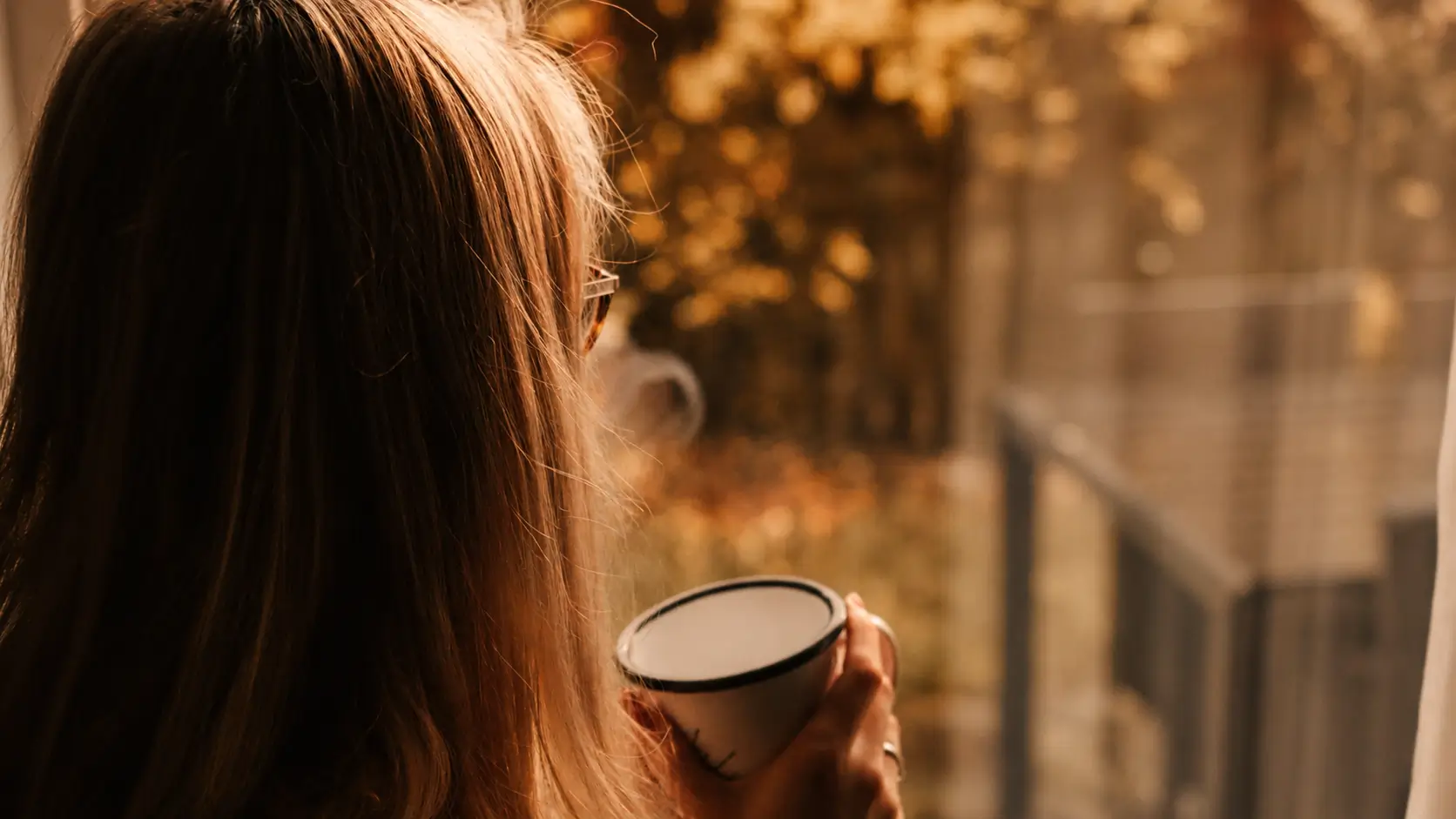 Woman holding a cup during a quiet moment in warm evening light