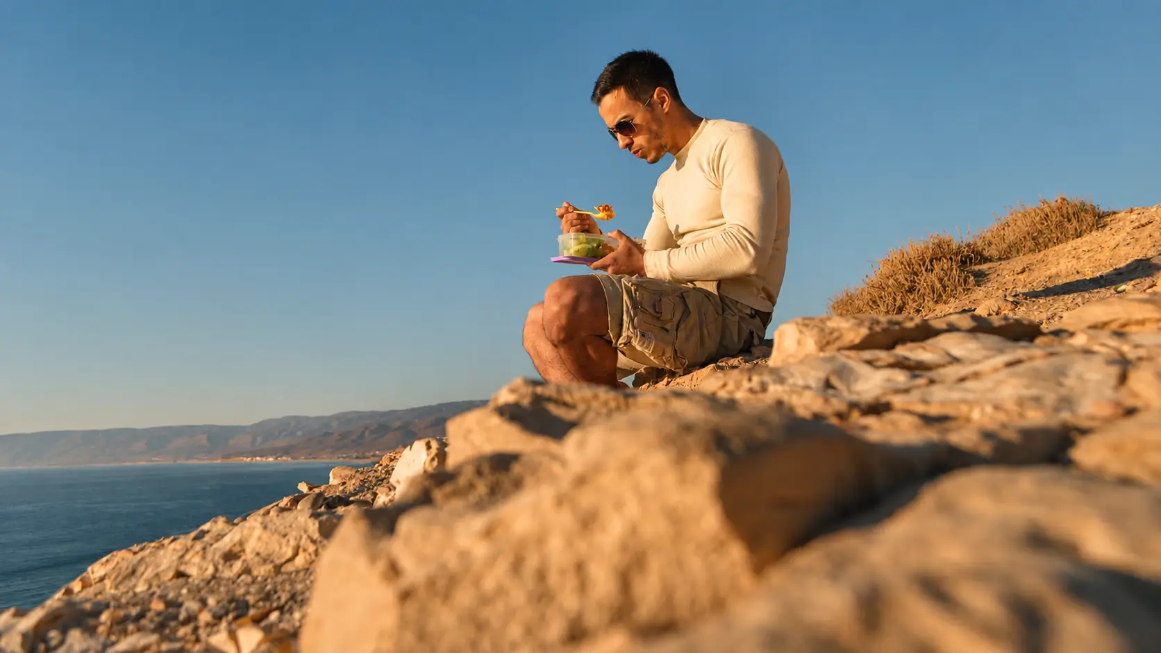 Man enjoying a simple meal outdoors overlooking the ocean
