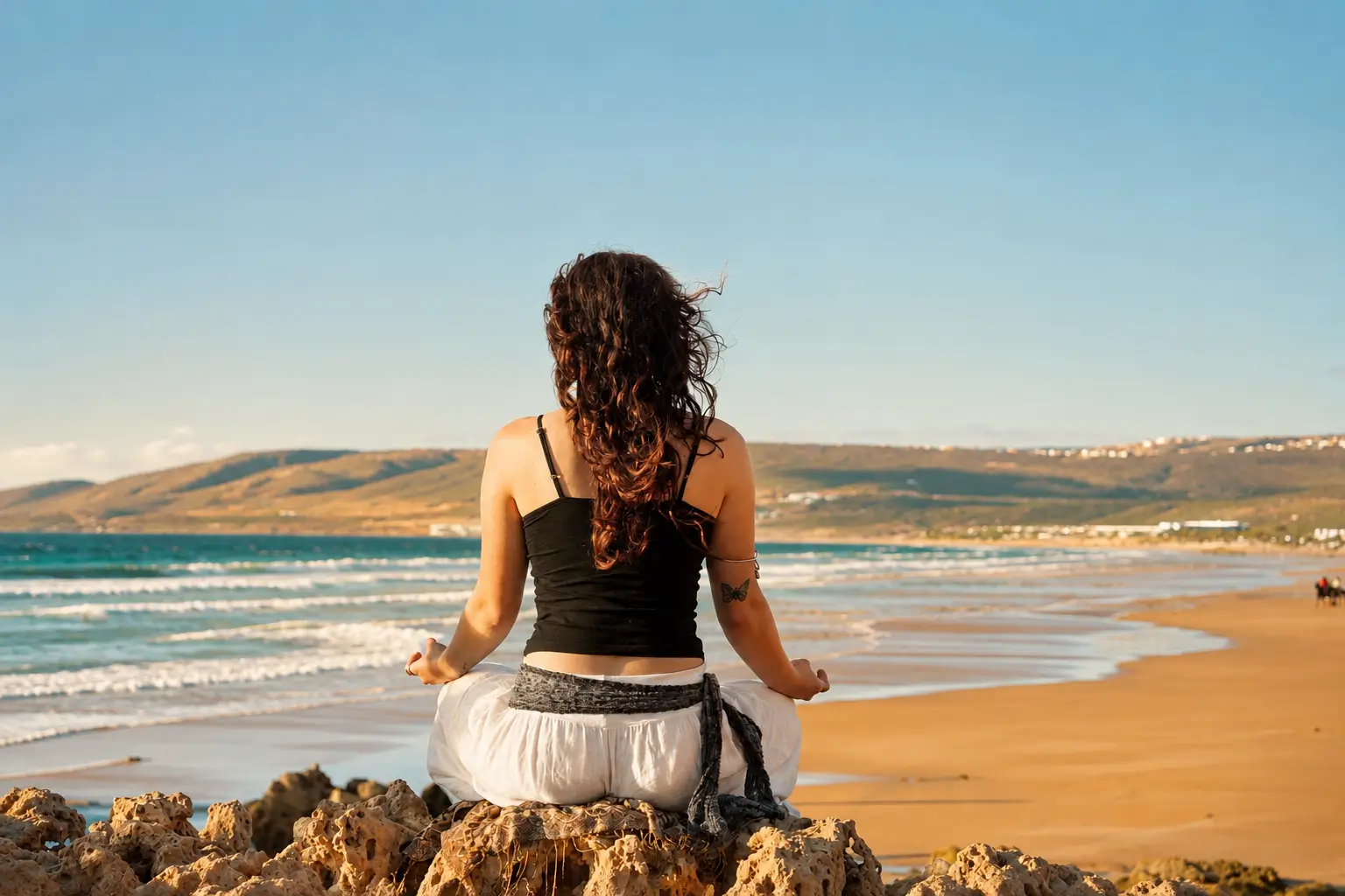 Woman meditating on rocks overlooking the ocean