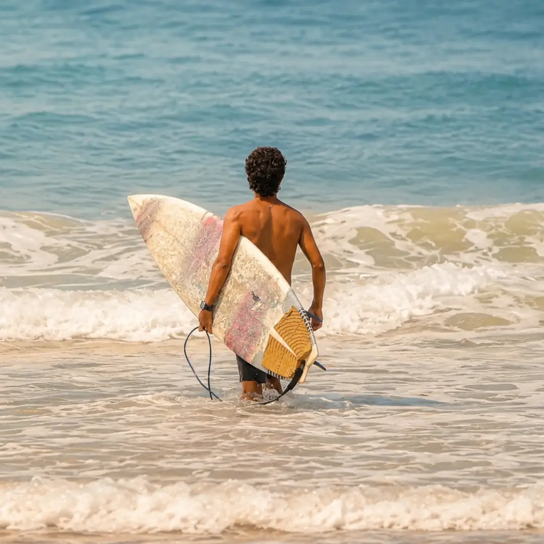 Surfer carrying a surfboard into the ocean