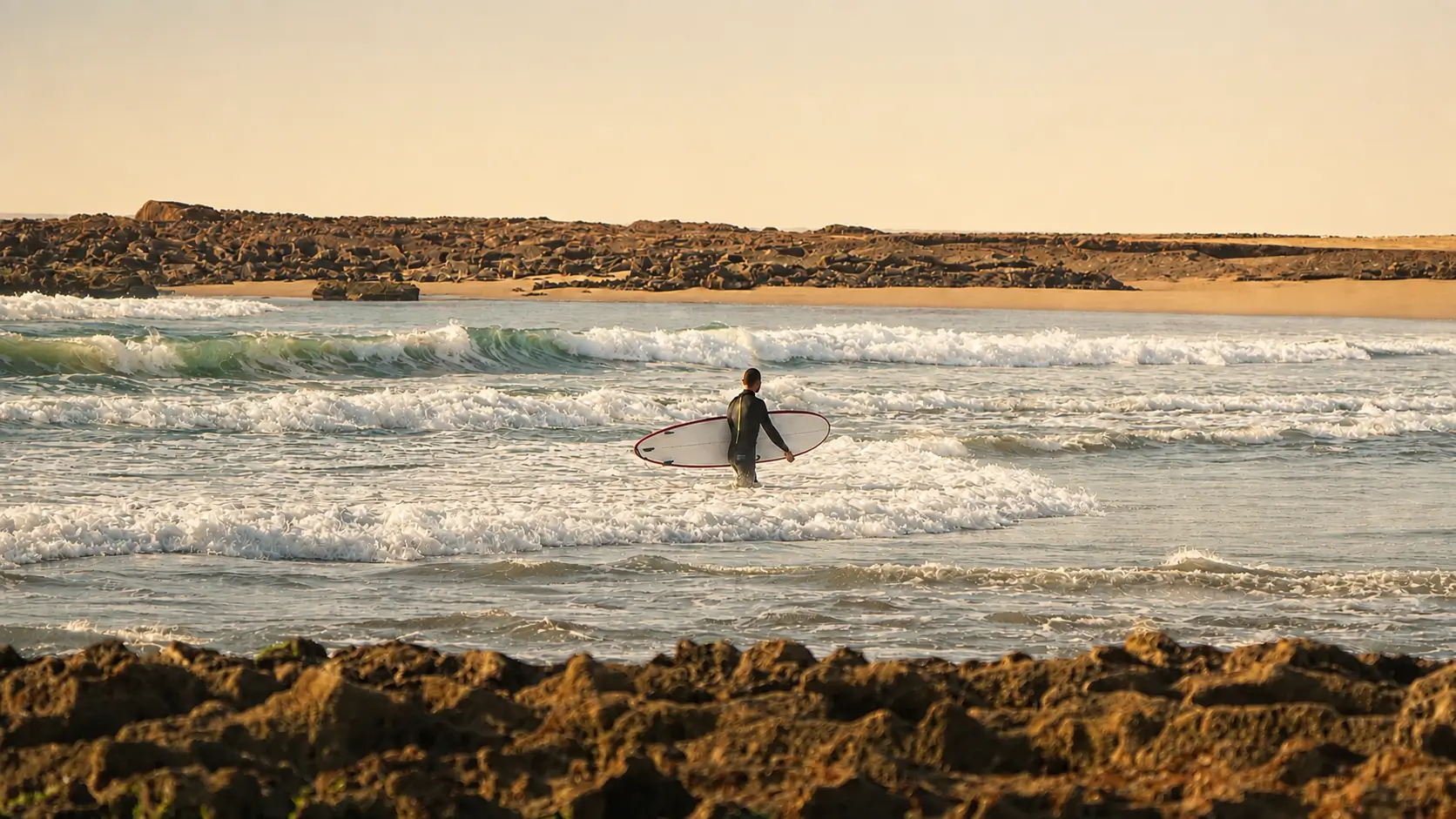 Surfer carrying a surfboard into the ocean after a surf session