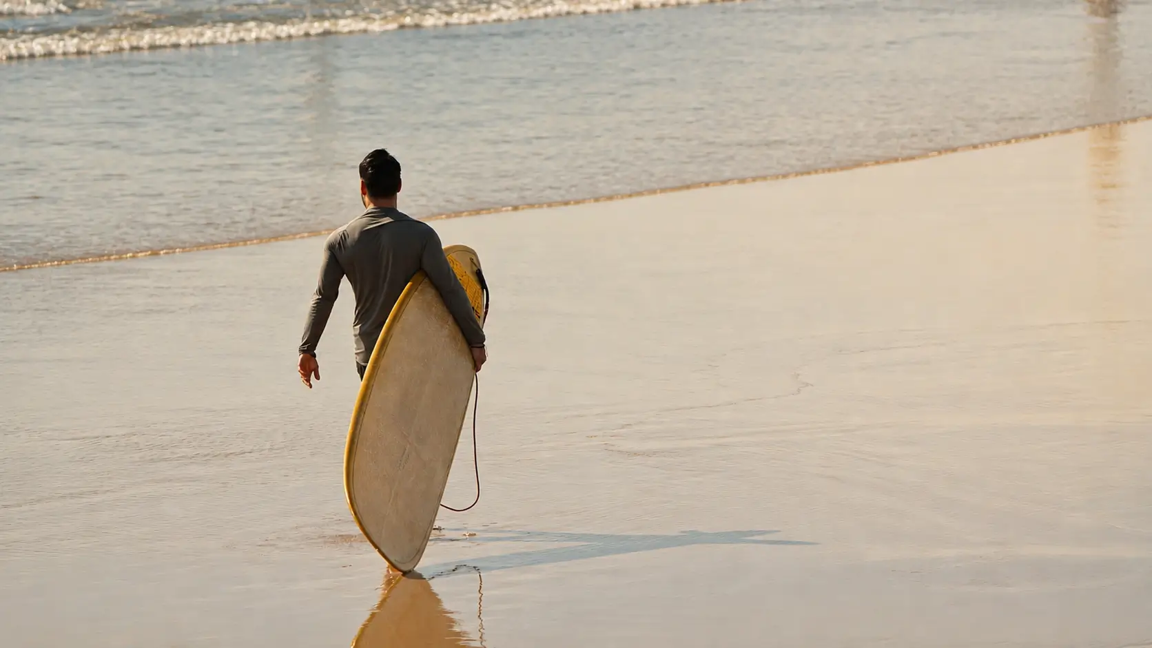 Surfer carrying a surfboard while walking toward the ocean