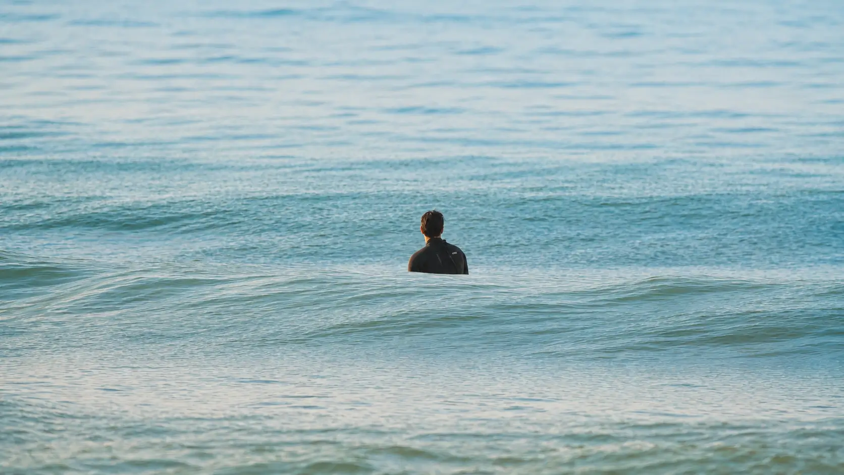 Surfer watching gentle waves roll across the ocean