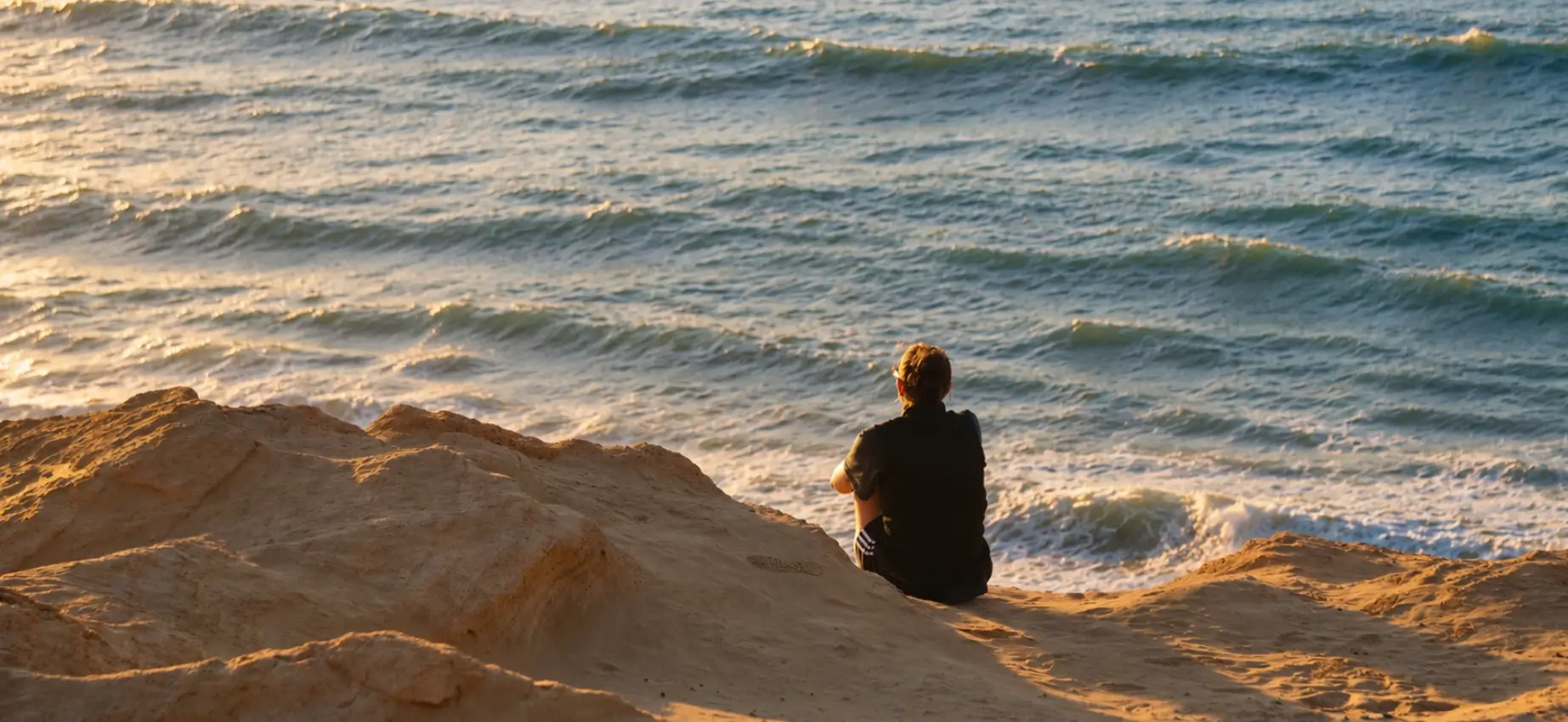 Person walking alone beside the ocean at dusk